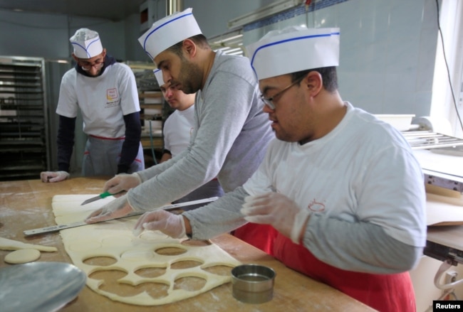 FILE - Ali Kerdi, 35, trains special needs students at a bakery in the southern city of Tyre, Lebanon, Dec. 18, 2018.