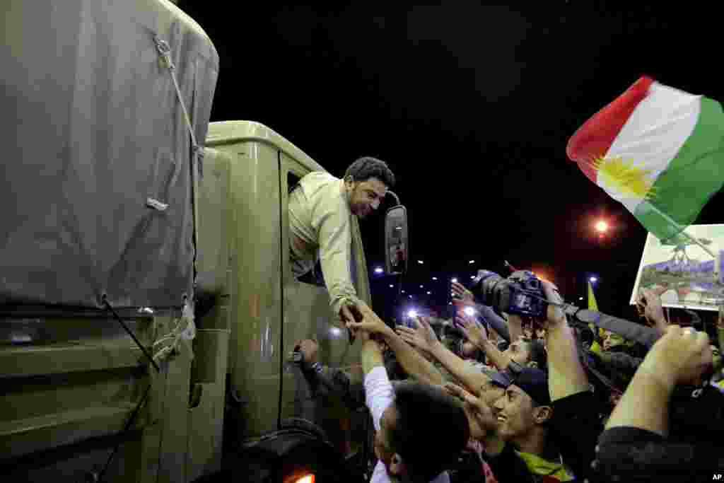 A Kurdish Peshmerga solider reaches out his hand to supporters, at the Ibrahim Khalil border crossing, in the Northern Kurdish Region of Iraq, Wednesday, Oct. 29, 2014.