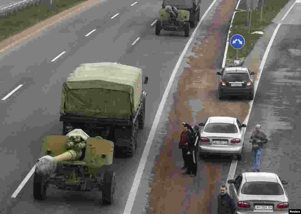 Motorists watch a Ukrainian military convoy pass by near the city of Donetsk, Ukraine, April 10, 2014. 