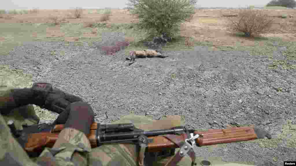 Des soldats tchadiens passent en voiture devant le corps d&#39;un homme qu&#39;ils disent être un combattant de Boko Haram tué par l&#39;armée tchadienne au cours des combats à Gambaru, Nigeria, le 26 février 2015.