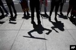 Protesters cast their shadows as they chant slogans during a rally outside the Millennium Biltmore Hotel in Los Angeles, where Attorney General Jeff Sessions was scheduled to speak, June 26, 2018.