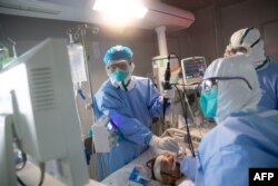 Medical staff treat a COVID-19 coronavirus patient at a hospital in Wuhan, in China's central Hubei province on March 19, 2020