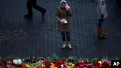 一位烏克蘭婦女在基輔街頭的紀念在抗議衝突中死亡抗議者的花圈前哭泣