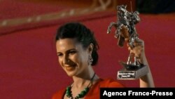 An unidentified woman hold the Golden Stallion of Yennenga trophy awarded to film director Khadar Ahmed of Somalia at the 27th FESPACO Panafrican Film and Television Festival for his film "The Gravedigger's Wife" on October 23, 2021, in Ouagadougou.