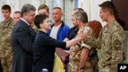 Newly-released Ukrainian pilot Nadiya Savchenko, center left, is congratulated by fellow servicemen in the Presidential Office in Kyiv, Ukraine, May 25, 2016. Ukrainian President Petro Poroshenko is second left. Russia released Savchenko as part of a swap