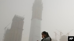 A woman covers her face with her hands to protect her from polluted air and a sandstorm in Beijing, May 4, 2017. Authorities in Beijing issued a blue alert on air pollution as sandstorm swept through the Chinese capital city Thursday morning.
