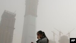 Một phụ nữ dùng tay che mặt tránh không khí ô nhiễm và bão cát tại Bắc Kinh, ngày 4/5/2017. 