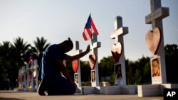 Ernesto Vergne prays at a cross honoring his friend Xavier Emmanuel Serrano Rosado and the other victims at a memorial to those killed in the Pulse nightclub mass shooting a few blocks from the club in Orlando, Florida, June 17, 2016. (AP Photo/David Goldman)