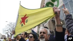 FILE - A man holds a flag of the YPG, a Syria-based Kurdish militant group, during a protest against Turkish President Recep Tayyip Erdogan in front of the Brookings Institution in Washington, where Erdogan was speaking, March 31, 2016.