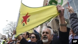 FILE - A man holds a flag of the YPG, a Syria-based Kurdish militant group, during a protest against Turkish President Recep Tayyip Erdogan in front of the Brookings Institution in Washington, where Erdogan was speaking, March 31, 2016.