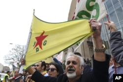 FILE - A man holds a flag of the YPG, a Syria-based Kurdish militant group, during a protest against Turkish President Recep Tayyip Erdogan in front of the Brookings Institution in Washington, where Erdogan was speaking, March 31, 2016.