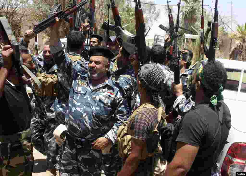 Iraqi security forces and volunteers shout slogans on the outskirts of the town of Udaim in Diyala province, Iraq, June 22, 2014.