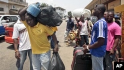 People walk with their belongings towards a railway station as they leave Abidjan, Ivory Coast. Rebel forces backing Ivory Coast's internationally recognized president were advancing toward the capital Wednesday, March 29, 2010