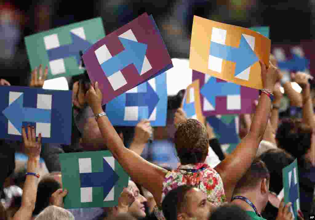 Attendees hold Clinton campaign signs as votes are cast during the second day of the Democratic National Convention