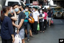 People wait along a street to buy protective face masks at a store in Manila, Philippines on Thursday, Jan. 30, 2020. Health Secretary Francisco Duque confirmed the Philippines' first case of a new virus that has infected thousands in China. (AP Photo)