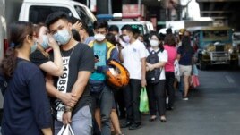 People wait along a street to buy protective face masks at a store in Manila, Philippines on Thursday, Jan. 30, 2020. Health Secretary Francisco Duque confirmed the Philippines' first case of a new virus that has infected thousands in China. (AP Photo)