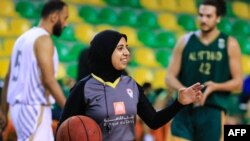 L'arbitre égyptienne de basket-ball Sarah Gamal fait des gestes en tenant un ballon lors d'un match entre les équipes d'Al-Ittihad et d'Al-Geish à l'arène Al-Ittihad Al-Sakandari, dans le nord du pays, le 17 avril 2021.