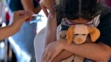 A girl hugs her stuffed toy as she gets a shot of the Pfizer COVID-19 vaccine at a community health center, in Brasilia, Brazil, Jan. 16, 2022.