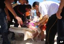 FILE - Injured people are treated after gunmen opened fire at beach near the Imperial Marhaba hotel in Sousse, Tunisia, June 26, 2015.