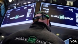 Specialist John O'Hara, wears Shake Shack promotional hat, sunglasses and vest as he works at his post on the floor of the New York Stock Exchange Friday, Jan. 30, 2015.