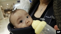 Miyako Ikeda feeds her baby Ryutaro drinking water after buying bottled water at a supermarket in Tokyo, March 25, 2011.