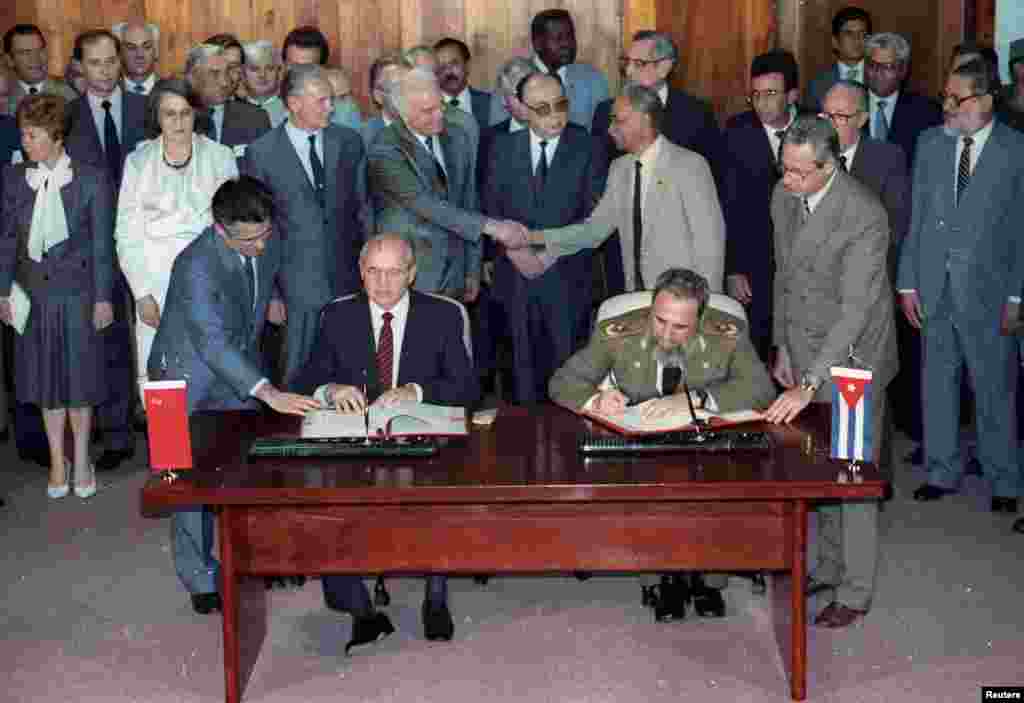 Soviet leader Mikhail Gorbechev and President Fidel Castro sign a friendship and cooperation treaty as Soviet Foreign Minister Edward Shevardnadze and Cuban Politburo member Juan Almeda shake hands, Havana, April 4, 1989.