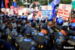 Anti-riot police block protesters holding placards against U.S. President Donald Trump outside the U.S. embassy in metro Manila, Philippines, Jan. 20, 2017.