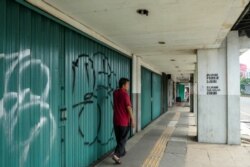 Seorang pria berjalan melewati toko-toko yang sepi setelah penerapan Pembatasan Sosial Berskala Besar (PSBB) di Jakarta, 10 April 2020. (Foto: AFP)