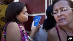 A woman holding her Cuban passport lines up with others at a migration office in Havana, Cuba, Monday, Jan. 14, 2013.