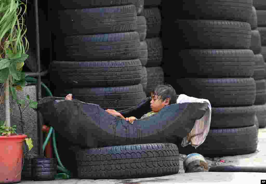 A Filipino girl takes a dip in a used tire at a vulcanizing shop in suburban Manila, Philippines.