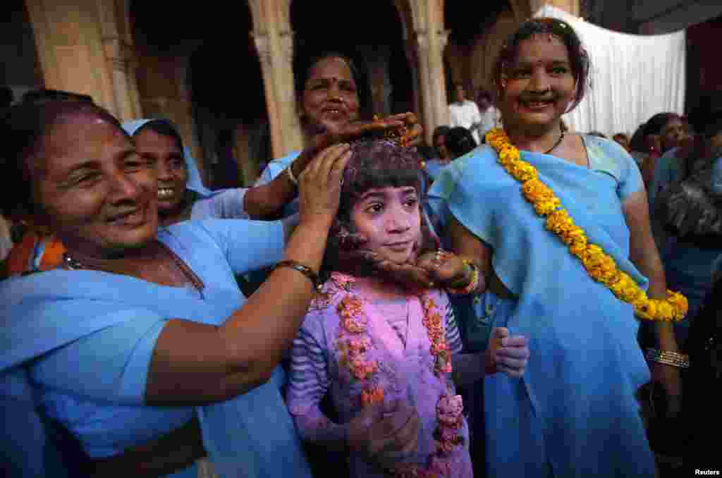 A boy covered in colored powder poses with a group of widows during a Holi celebration, March 24, 2013.