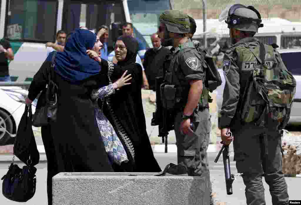 A Palestinian woman argues with an Israeli border policeman near the scene where two Palestinians where shot dead by Israeli forces near Qalandia checkpoint near the West Bank city of Ramallah.