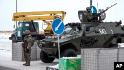 一个哨卡的哈萨克斯坦士兵站在一辆军车旁。（2022年1月7日）