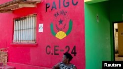 FILE - Dominga Lima, a member of the African Party for the Independence of Guinea and Cape Verde (PAIGC), sits in front of the party's logo at a campaign building in Bissau, Guinea-Bissau.