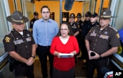 Flanked by Rowan County Sheriff's deputies, Rowan County Clerk Kim Davis, center, with her son Nathan Davis standing by her side, makes a statement to the media at the front door of the Rowan County Judicial Center in Morehead, Kentucky, Sept. 14, 2015.