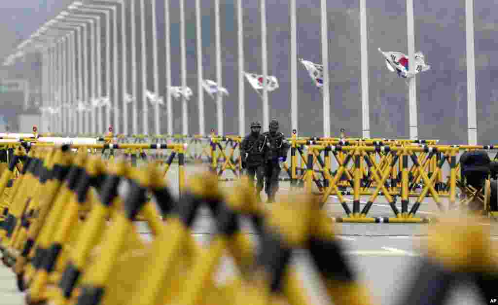 2013年4月15日，韩国陆军士兵走过首尔以北的坡州板门店边界村附近的统一桥上的路障。