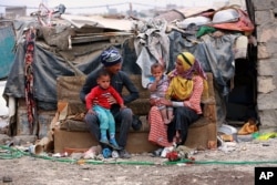 Hammadi Abdullah, 32, and his family sit outside their hut in an encampment outside Baghdad, Iraq, Feb. 12, 2018.