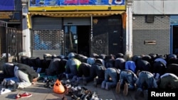 FILE - Muslims genuflect outside a mosque during Friday prayers in London.