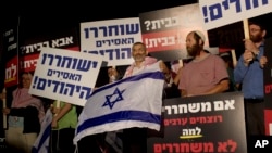 FILE - Israeli politician Michael Ben Ari, center, holds an Israeli flag while attending a demonstration against the release of Palestinian prisoners from Israeli jails, outside the Ofer military prison near the West Bank city of Ramallah, Oct. 29, 2013. 