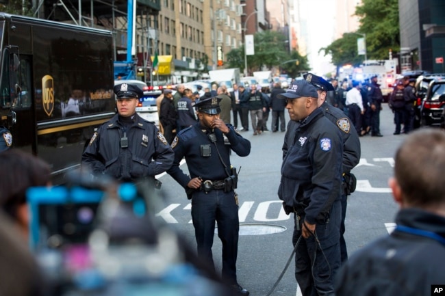 Officers watch over the scene outside the Time Warner Center, Oct. 24, 2018, in New York. Law enforcement officials say a suspicious package that prompted an evacuation of CNN's offices is believed to contain a pipe bomb.