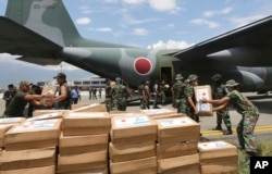 Indonesian and Japanese military personnel unload relief aid from a Japan Air Force cargo plane at the Mutiara Sis Al-Jufri airport in Palu, Central Sulawesi, Indonesia, Oct. 6, 2018.