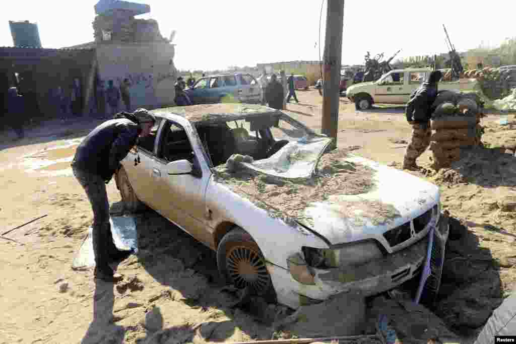 A man looks at a damaged car near a military base 50 km outside Benghazi, after a suicide bomber detonated a truck packed with explosives at an army checkpoint, Barsis, Libya, Dec. 22, 2013.&nbsp;
