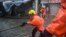 Fire rescue members prepare a rope to help people cross a flooded street at the village of Lei Yu Mun during Typhoon Mangkhut in Hong Kong, Sept. 16, 2018.