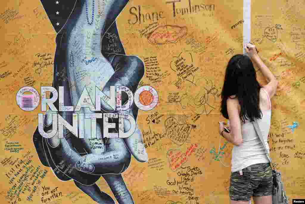 Mary Beth Nickerson signs the wall outside of Pulse Nightclub while visiting the memorial on the one year anniversary of the shooting in Orlando, Florida.