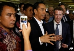 Presiden Joko Widodo, tengah, berbicara dengan CEO Facebook Mark Zuckerberg, kanan, selama kunjungan mereka ke sebuah pasar di Jakarta. (Foto: AP)