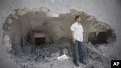 In this photo made on a government organized tour, a man stands next to a hole in a wall at the Gadhafi family compound in a residential area of Tripoli, Libya, Sunday, May 1, 2011. Libyan leader Moammar Gadhafi escaped a NATO missile strike in Tripoli th