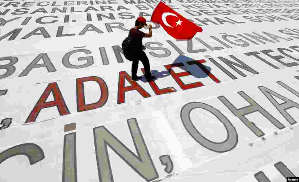 지난 9일(현지시간) 터키 최대도시 이스탄불에서 국기를 든 청년이 대형 현수막 위를 걷고 있다. 야당인 공화인민당 케말 클르치다르올루 대표는 지지자들과 함께 야당 정치인 구속에 도보 항의하는 25일간의 &#39;정의의 행진&#39;을 이날 마무리했다. &nbsp;