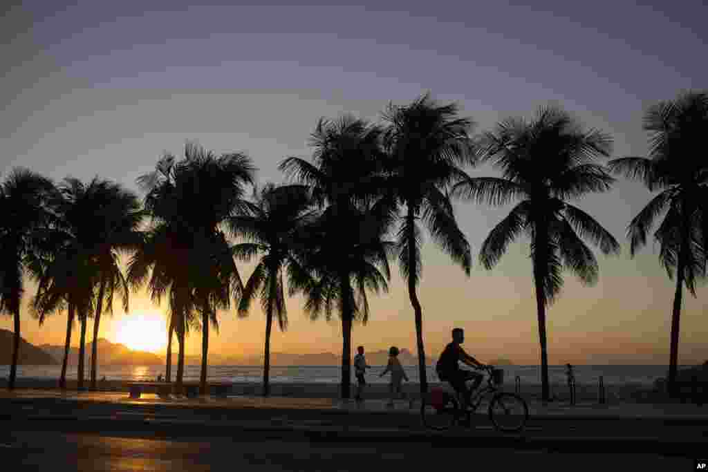 People exercise along Copacabana beach as the sun rises in Rio de Janeiro, Brazil.