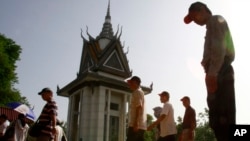 FILE - Foreign tourists walk through Choeung Ek stupa, which stores thousands of human bones and skulls of the Khmer Rouge's victims in the outskirt of Phnom Penh, Cambodia, June 25, 2011. 