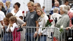 People at Oslo Cathedral pay their respects to victims of last week's bomb attack and shootings in Norway, July 27, 2011